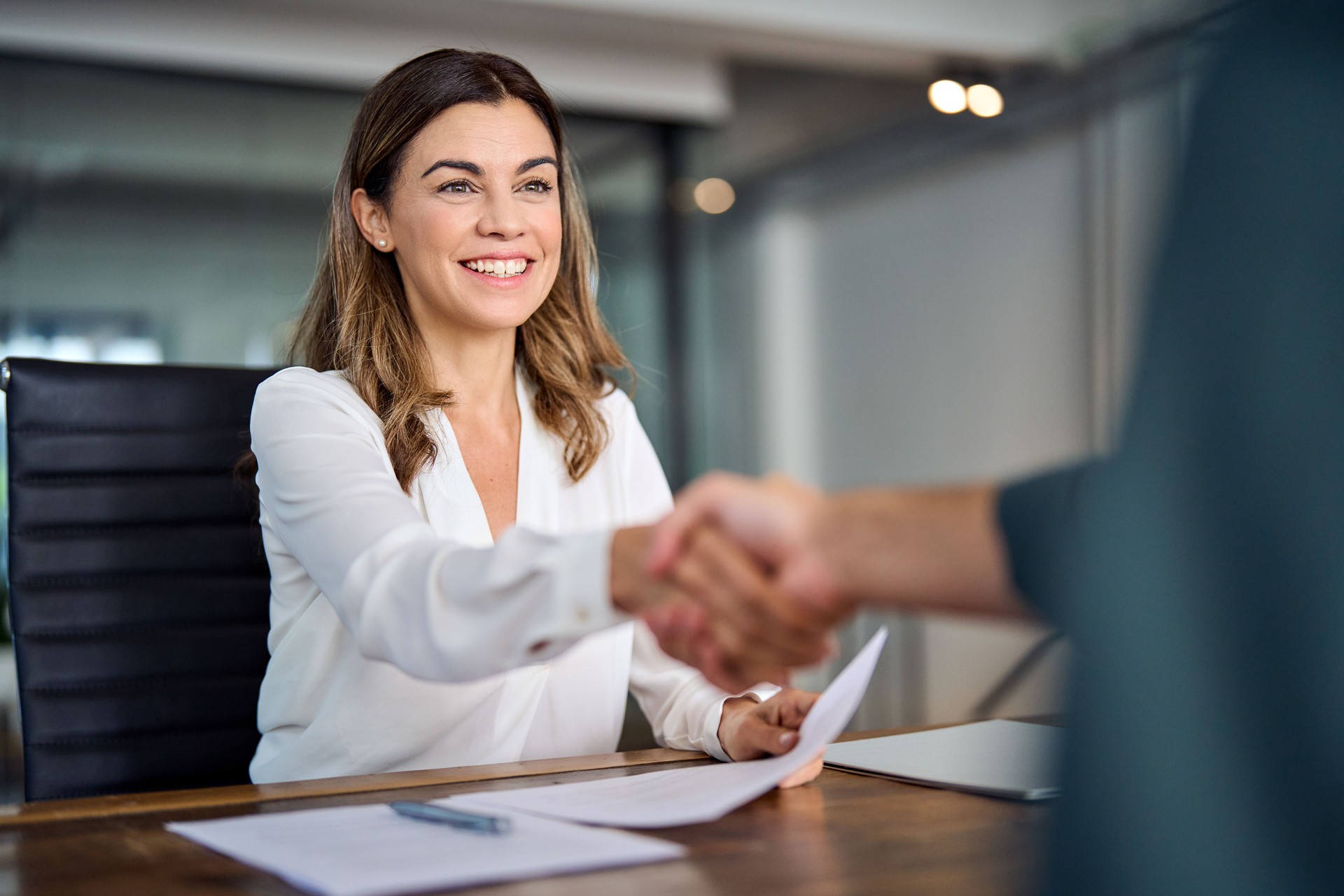 Happy mid aged business woman manager handshaking at office meeting.